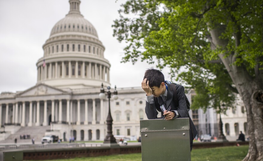 A student from Wisconsin takes a break in front of the Capitol Wednesday. Republican and Democratic negotiators appear ready to pass a one-week funding measure to keep the government open.