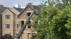 A construction worker balances atop a roof. States and cities are loosening building code requirements in an effort to lower construction costs and boost affordable housing.
