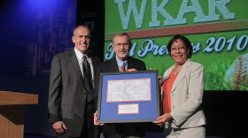 MSU Provost Kim Wilcox (left) and WKAR General Manager DeAnne Hamilton (right) presented David Hollister with a framed replica of a blueprint of Oldsmobile Park, home of the Lansing Lugnuts and known today as Cooley Law School Stadium, on Aug. 31, 2010.