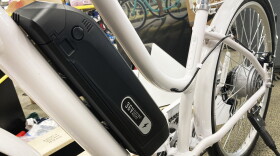 an electric motor sits along the frame of a white bicycle