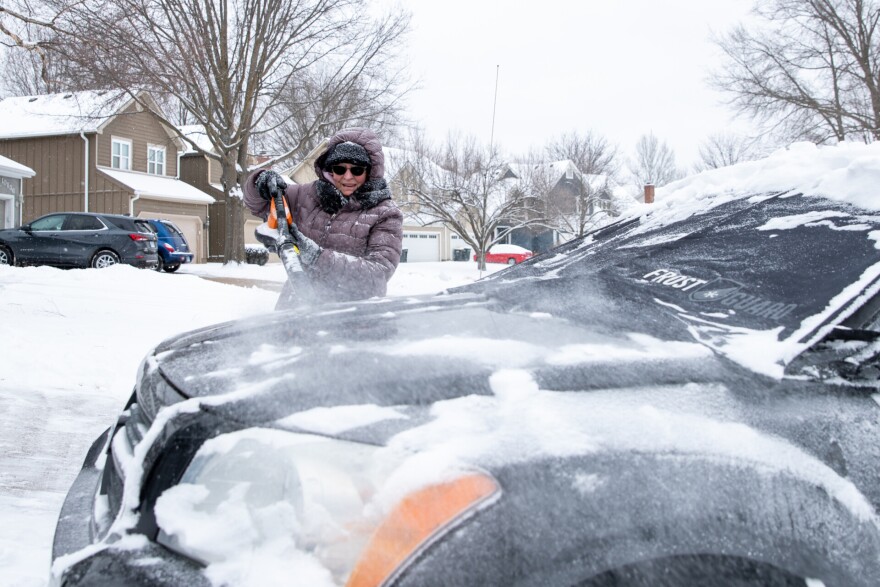 Vickie Paulson used a leaf blower to remove snow from her car on Wednesday, Feb. 12, in Overland Park.