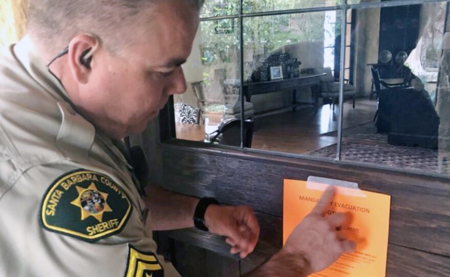 Santa Barbara County Sheriff's Deputy Mike Harris posts a notice on a home near Carpinteria, Calif., advising of the mandatory evacuation. flash flood warnings for the area were lifted around 9:45 a.m. ET, The Associated Press reports.
