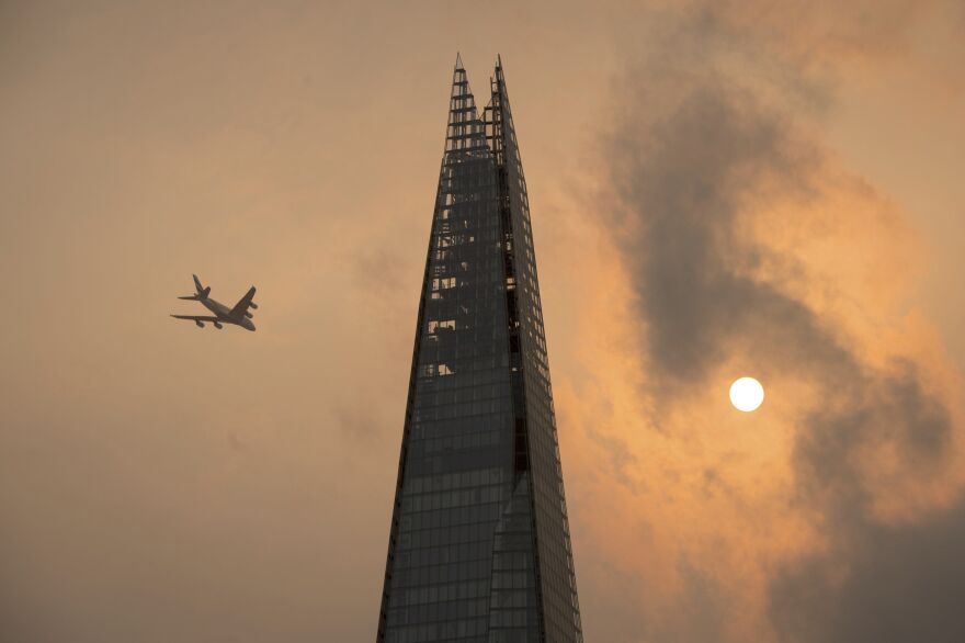 A plane flies past the Shard in central London on Monday amid skies that took on an unusual orange color caused by storm Ophelia.