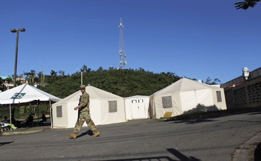 A Puerto Rico National Guard member walks past the health clinic in Vieques, operating out of tents in a parking lot.
