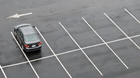 Single car in otherwise empty parking lot, in the rain