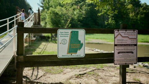 A sign on a fence in front of a river