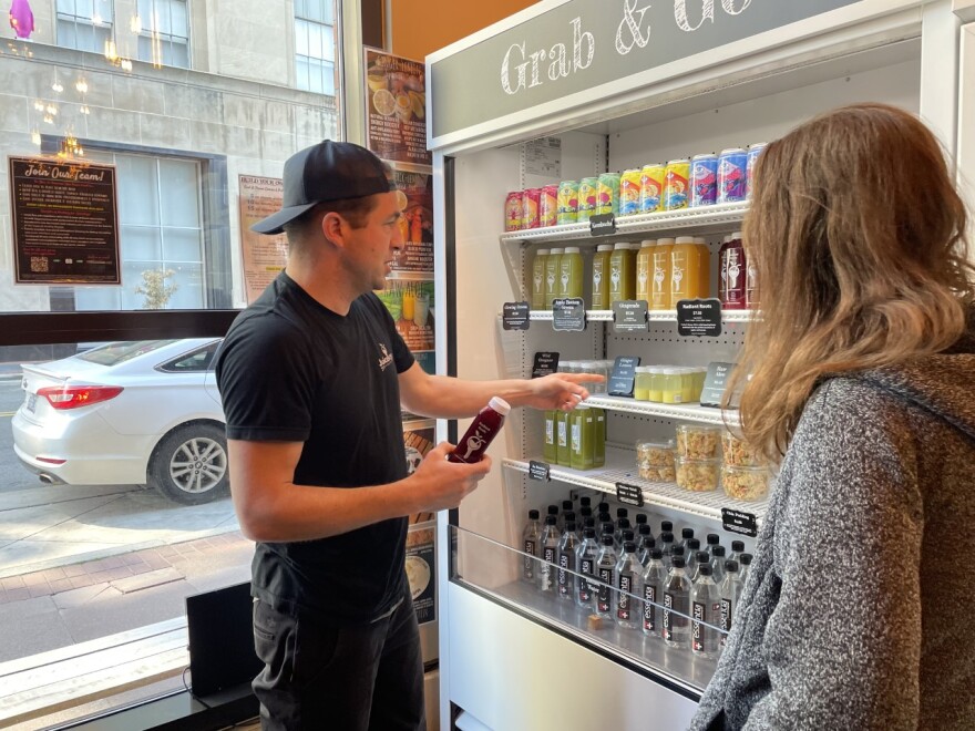 Store owner Chris Young tells customer about variety of juices. 