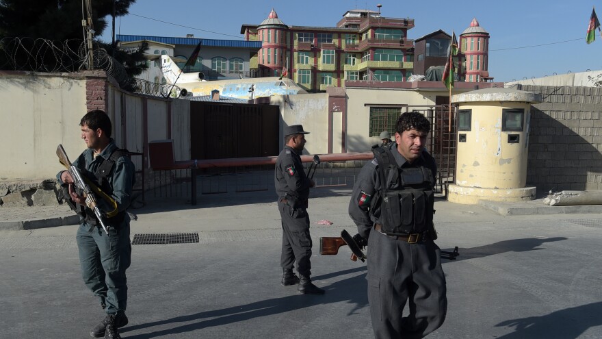 Afghan policemen stand guard near an entrance gate at the Shamshad TV Network after gunmen who were reportedly disguised as policemen stormed the media outlet in Kabul on Tuesday.
