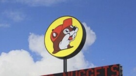 A circular yellow sign with a beaver wearing a hat atop a digital sign that reads "Beaver Nuggets."