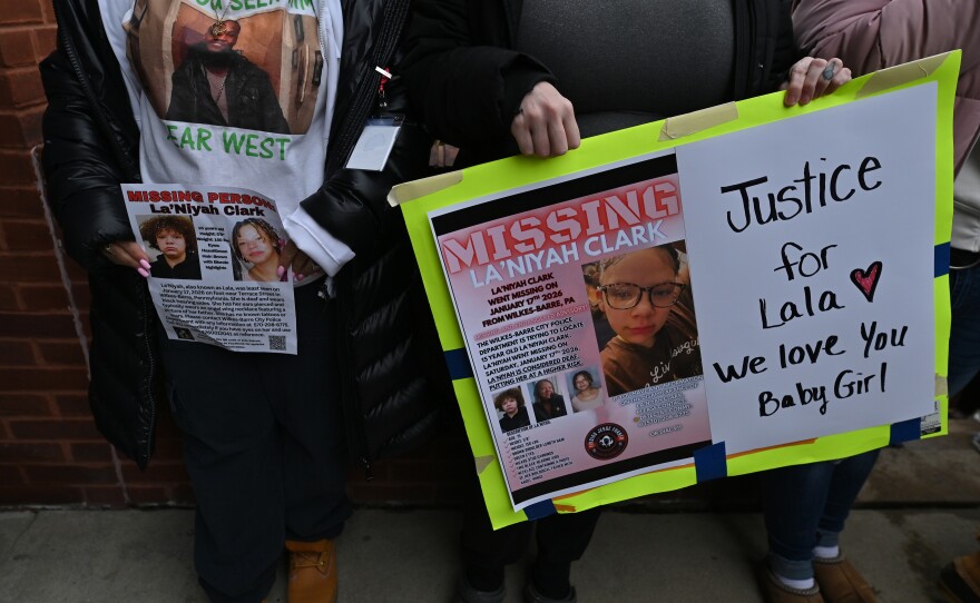 People who came out to support La'Niyah Clarks families hold signs for the missing teenager. A woman wears a shirt with a photo of Yiear West, who is also missing.