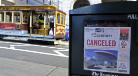 A newspaper headline announcing the closure of large events is displayed as a cable car goes down California Street, Friday, March 13, 2020, in San Francisco. (Eric Risberg/AP Photo)
