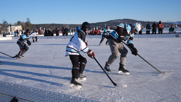 Players battle for a puck on the ice at the 17th annual New England Pond Hockey Classic