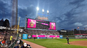 A wide shot of sold-out Progressive Field under the lights with Banana Ball logos on the scoreboard.