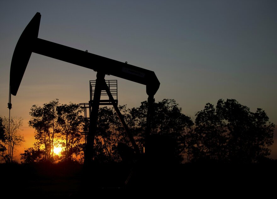 FILE - In this Feb. 19, 2015 file photo, the sun sets behind an oil well in a field near El Tigre, a town within Venezuela's Hugo Chavez oil belt, formally known as the Orinoco Belt. (AP Photo/Fernando Llano, File)