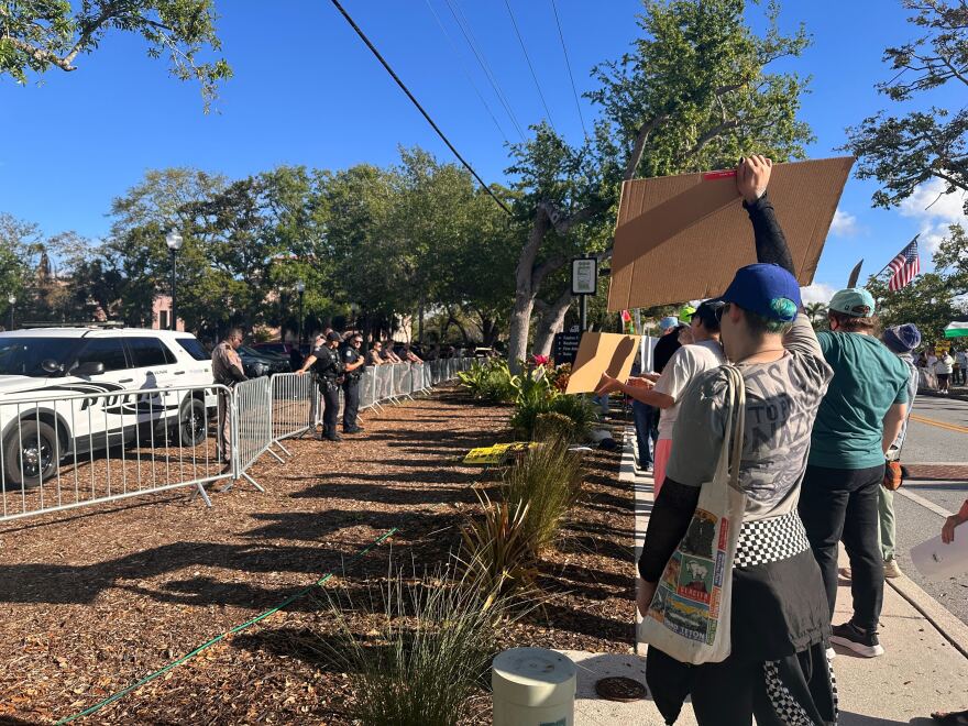 Protesters holding signs on a grassy area