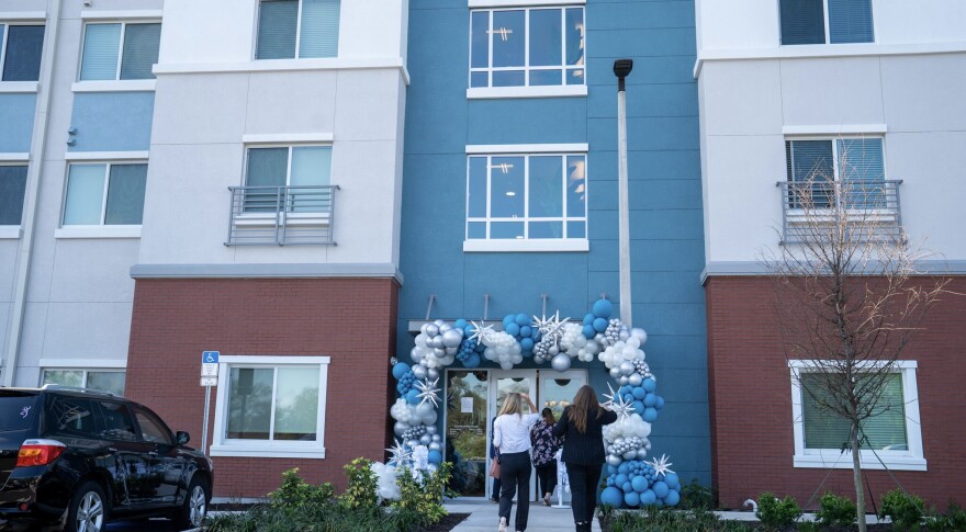 Outside apartment complex with people walking in and a balloon arch across the entryway 