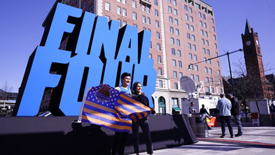 Fans pose with a Final Four logo before a college basketball game during the Final Four round of the NCAA tournament at Lucas Oil Stadium in Indianapolis, Saturday, April 3, 2021.