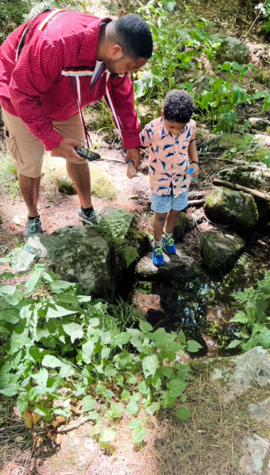Mack Scott III with his son, Mack Scott IV, on the Narragansett reservation drinking from a sacred spring.