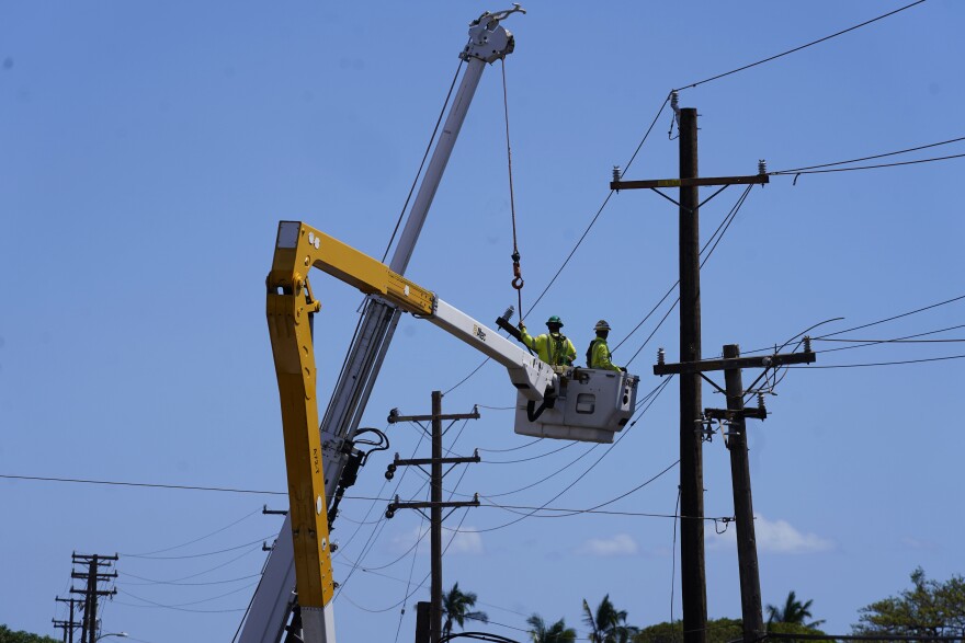Linemen work on poles, Aug. 13, 2023, in Lahaina, Hawaii, following a deadly wildfire.