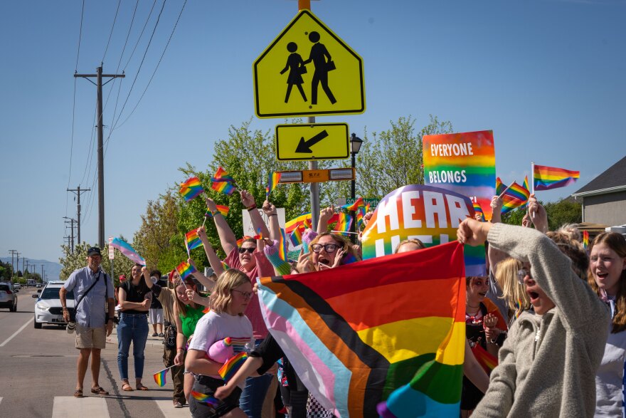 Skyridge High School students cheer and wave their rainbow flags as cars drive by on the street in front of the school in Lehi, Utah, May 15, 2023.