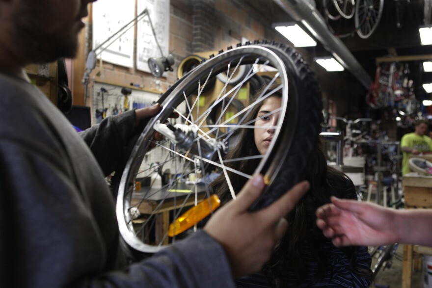 Scavo students change a tire during physics class at the Des Moines Bike Collective.