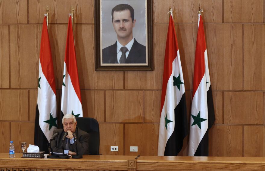 At a press conference in Damascus on Thursday, Syrian Foreign Minister Walid Muallem denied that government forces had used chemical weapons. A portrait of Syrian President Bashar Assad is seen hanging on the wall behind him.