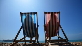 People relax in deck chairs on the beach. (Carl Court/AFP via Getty Images)