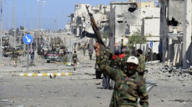 <p>In Sirte, fighters loyal to the new government celebrate after the town's defenses finally fell, and former leader Moammar Gadhafi was killed.</p>