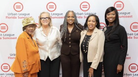 Four women standing in front of a Urban League of Florida Suncoast banner smiling 