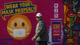 A man walks past a mural on how to wear a face mask to prevent the spread of coronavirus, in Soweto, South Africa, Saturday, May 15, 2021. (AP Photo/Themba Hadebe)