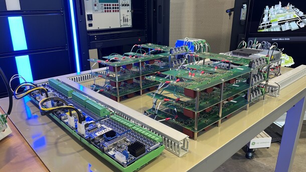 This is a stack of circuit boards on a table. There's some machinery and screens in the background. 