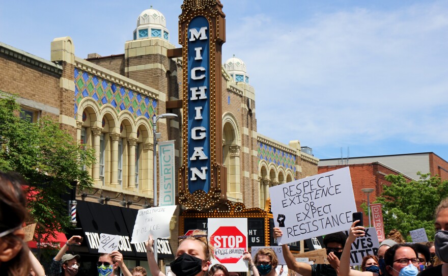 protesters marching through downtown ann arbor in front of the Michigan Theater sign