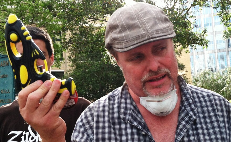 The Rev. Bruce Wright holds up a squirt gun and wears a surgical mask as examples of the everyday items that would be banned by the proposed "Clean Zone" ordinance during the week of the Republican National Convention.