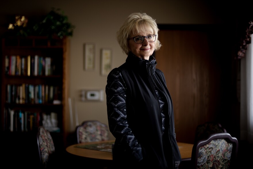 A blonde woman with glasses poses for a portrait.