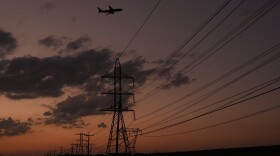 A plane passes over power lines at dusk in San Antonio, Monday, Aug. 3, 2026. (AP Photo/Eric Gay)