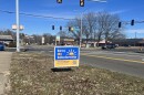 A "Save My Scholarship" sign sits at the intersection of John H. Gwynn Jr Ave. and MacArthur Highway in Peoria.