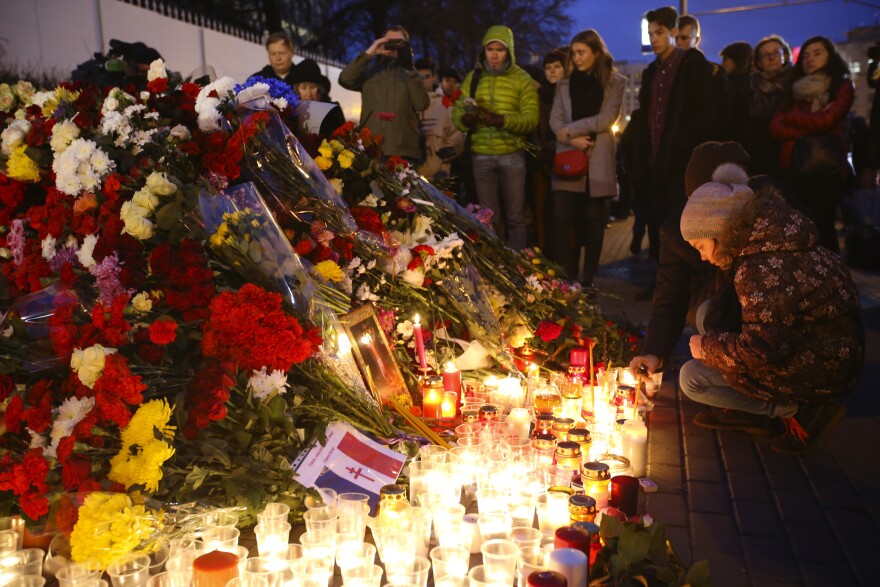 People lay flowers and light candles outside the French Embassy in Moscow, Russia.