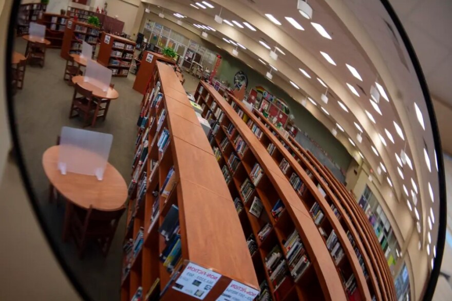 A school library is seen reflected in a convex security mirror.