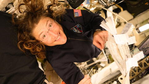 NASA astronaut Christina Koch smiles at the camera as she holds a pipette and saliva booklet for the Artemis II Immune Biomarkers study. Samples will be analyzed for proteins, enzymes, and other biomarkers that monitor immunity, inflammation, nutritional status, bone health, and radiation effects, to determine how crewmembers adapted to deep spaceflight conditions.