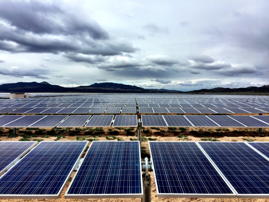 A large solar farm, with solar panels stretching out in the distance towards far-away mountains.