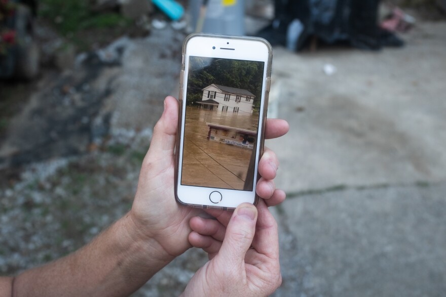 Derena Dunbar shows a cell phone photo of her aunt's home damaged during the recent flood in Millstone, Ky.