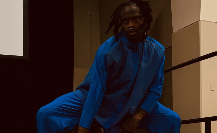 An African American man wearing all blue dances on a stage