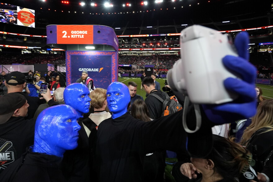 Members of the "Blue Man Group" take a photo with San Francisco 49ers tight end George Kittle during NFL football Super Bowl 58 opening night Monday, Feb. 5, 2024, in Las Vegas. The San Francisco 49ers face the Kansas City Chiefs in Super Bowl 58 on Sunday.