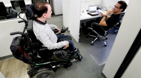 In this May 18, 2018, photo, Miles Thornback, left, who has cerebral palsy, works on marketing campaigns for agents talks with Jordan Wilson at RE/MAX Prestige real estate office in Costa Mesa, Calif. Thornback got hired three years ago at the real estate agency after the owners heard that he’d spent six years applying for jobs at hundreds of companies and finding nothing but negative mindsets.