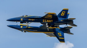 Two Blue Angel jet planes fly in tandem with one upside down directly below the other like a reflection