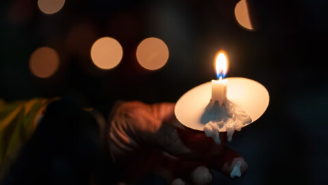 Candle wax melts onto an attendee’s finger during a vigil at Drake Park after three children and a teacher were killed in a mass shooting at Silver Rail Elementary School in Bend, Ore. on Oct. 15, 2026. The suspected shooter was a 16-year-old who entered the school and was killed by an armed bystander, bringing the total number of deaths to five.