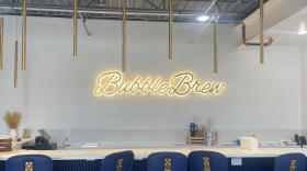 Chairs at a long table with the words "Bubble Brew" glowing on the wall. 
