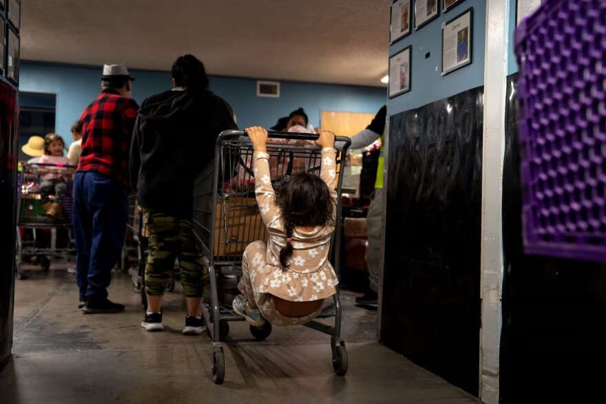 FILE - A child plays on her mother’s shopping cart in line at the Ecumenical Ministries of Oregon’s Northeast Emergency Food Program food bank in Portland, Ore., on Tuesday, Oct. 21, 2025.