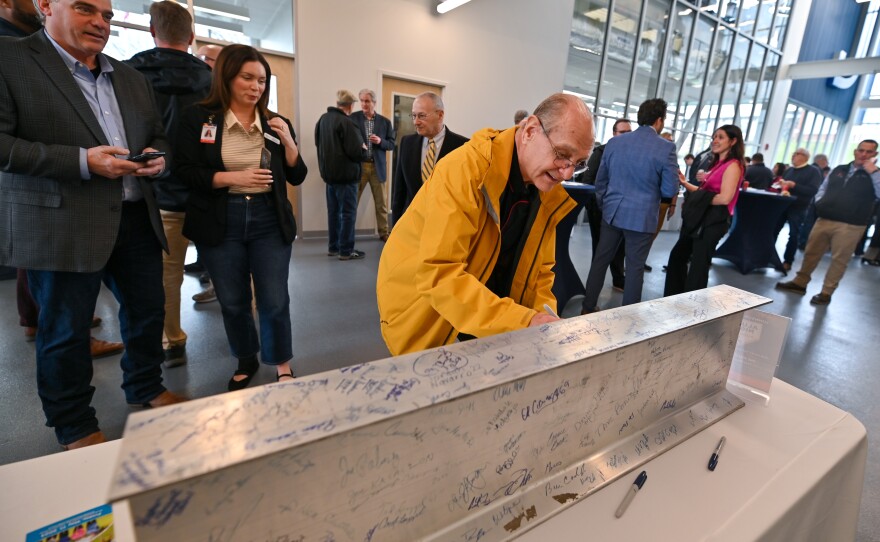 Former faculty member Rich Mishura signs an I-beam that will be displayed in the new Ideal Saldi Hall building at Johnson College.