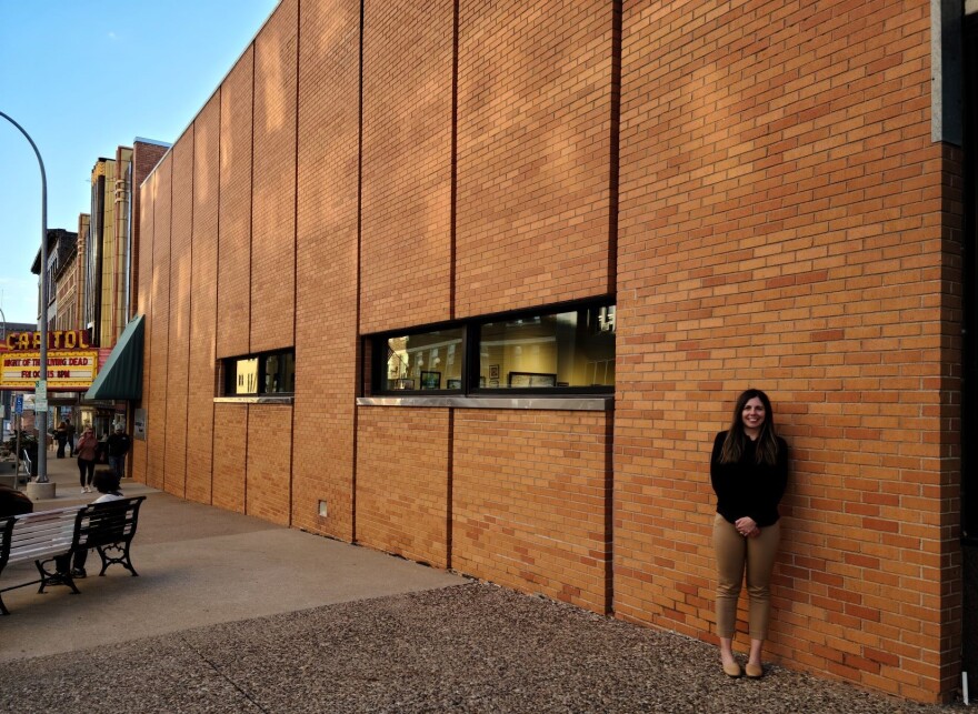 Elizabeth Pappas poses next to the wall that will soon be filled with art.